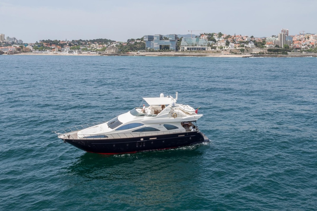 A boat filled with eager adventurers approaches the enchanting entrance of Benagil Cave, revealing the cave's majestic arch against the backdrop of the Algarve's crystal-clear waters