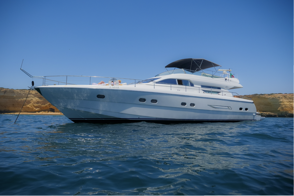 A boat filled with eager adventurers approaches the enchanting entrance of Benagil Cave, revealing the cave's majestic arch against the backdrop of the Algarve's crystal-clear waters